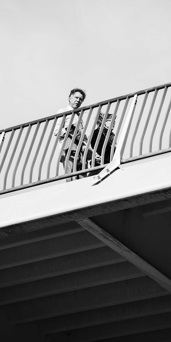 black-and-white man standing on bridge rotterdam