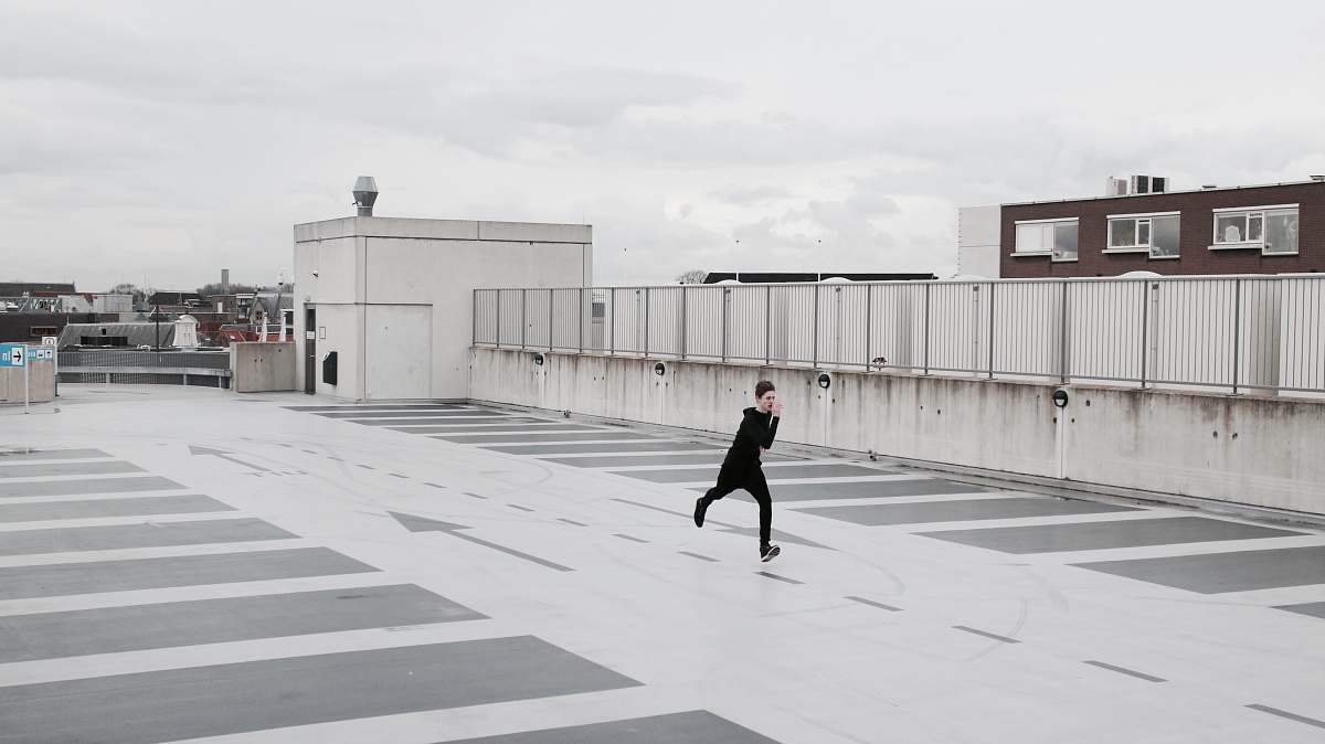 building person running on concrete lot during daytime parking