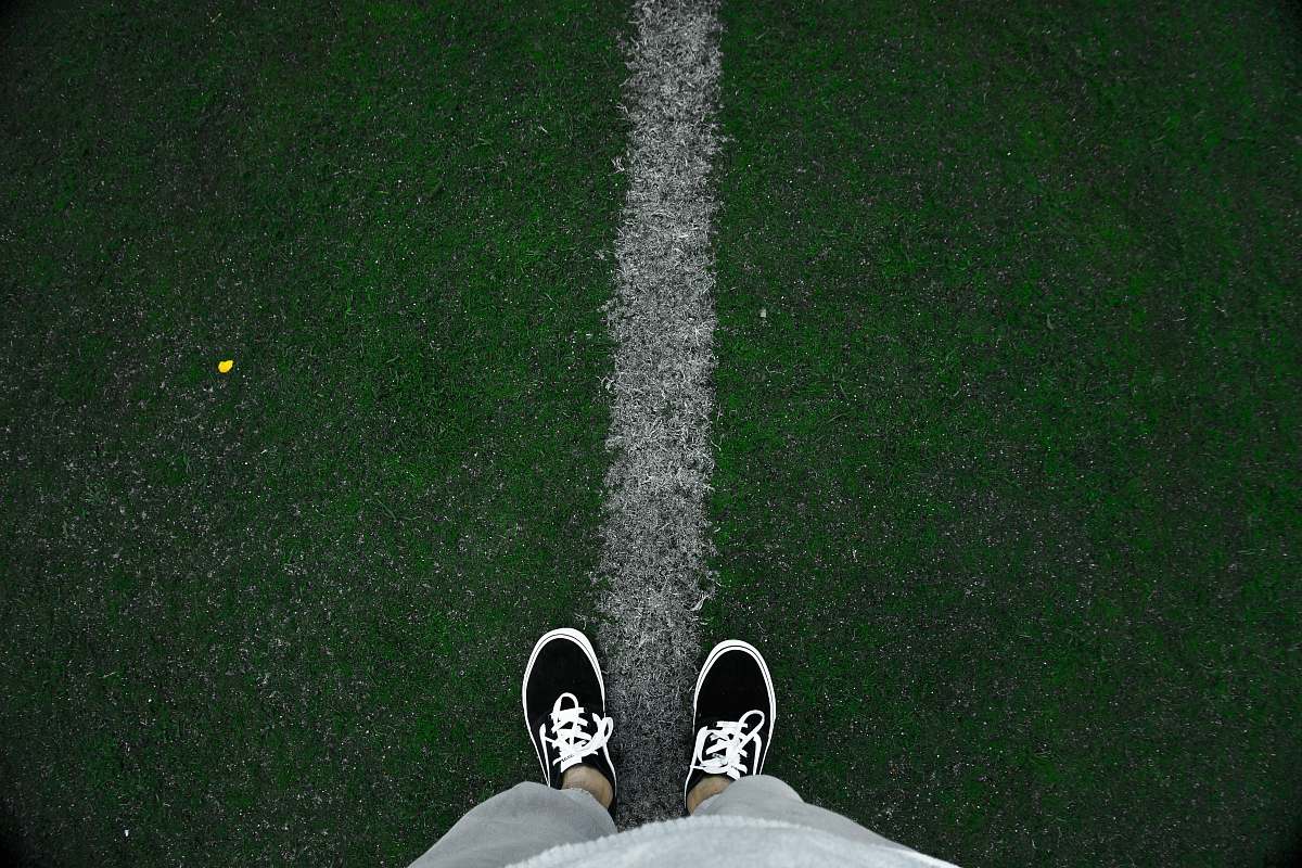 shoe person wearing black low-top sneakers standing on green grass at daytime clothing