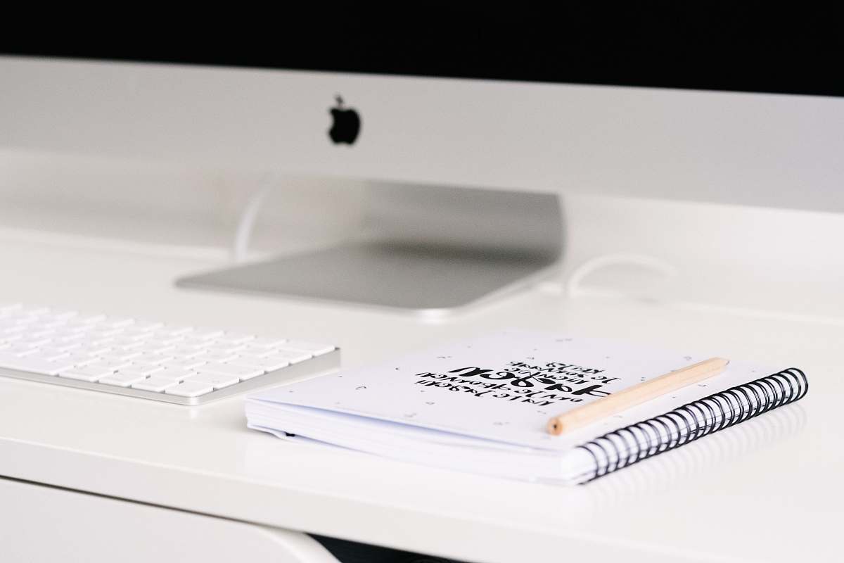 office white book beside iMac and keyboard on table notebook