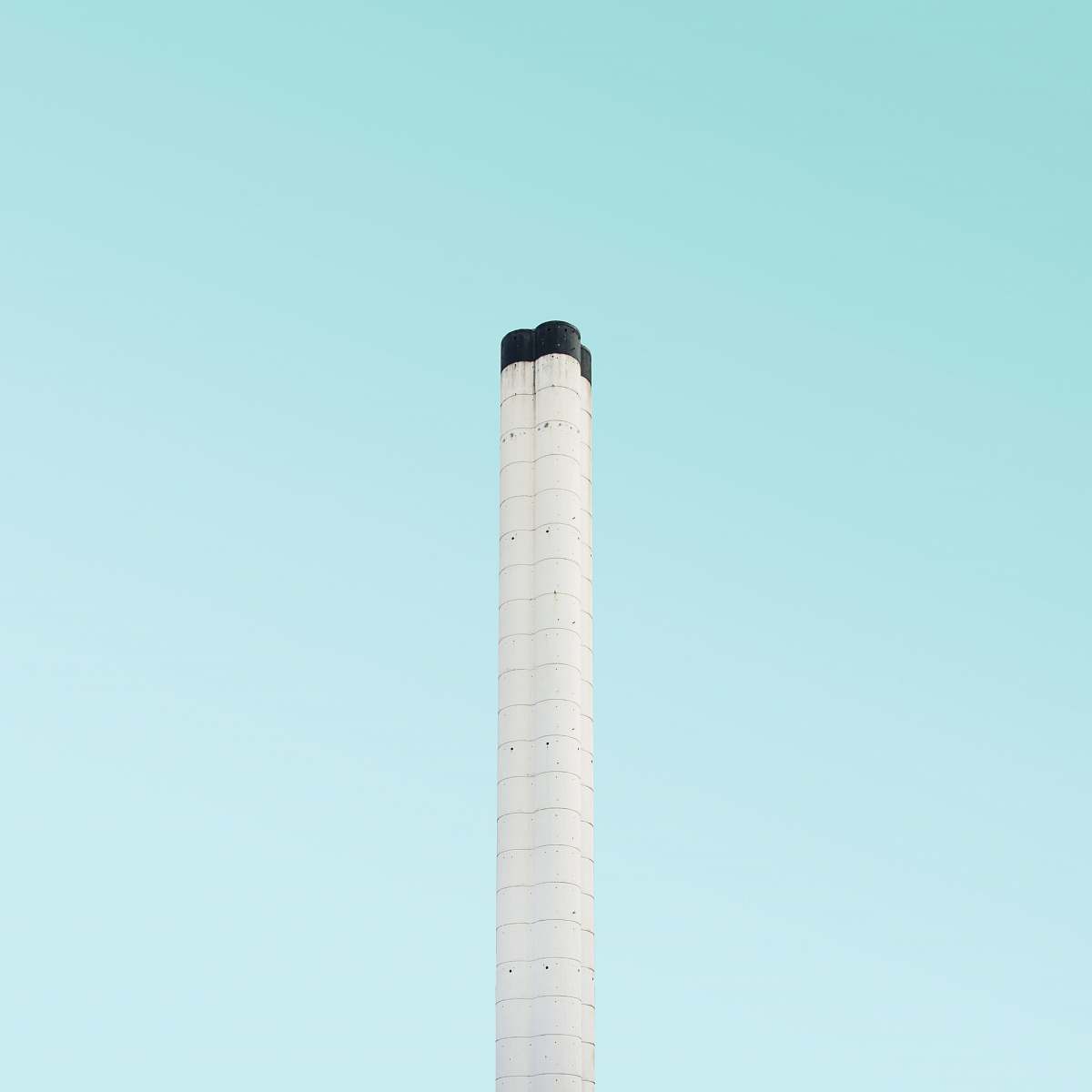 This stunning image features a striking white stick tower set against a vibrant teal background, complemented by a crisp white chimney that stands tall under a clear blue sky. The composition captures the essence of London's architectural beauty and urban landscape, making it ideal for travel magazines, city guides, and design projects. Use this photograph to evoke a sense of place and inspire wanderlust in your audience, showcasing the unique charm of London's iconic structures.