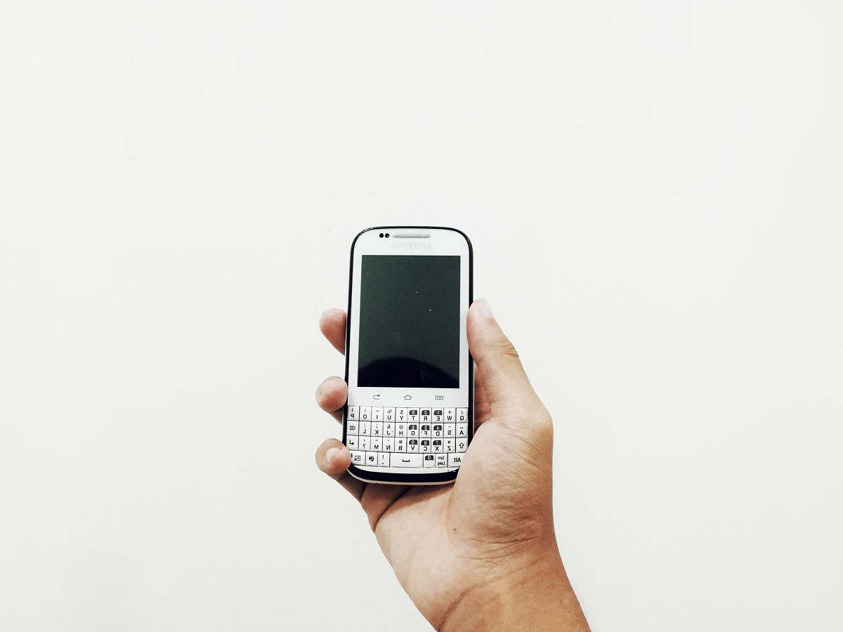 phone person holding white QWERTY phone white