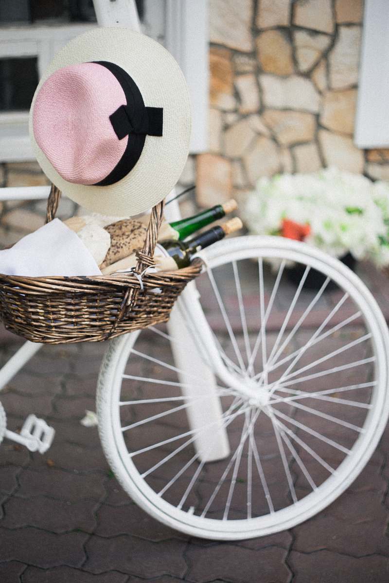 bicycle brown wicker basket with white, pink, and black sunhat besides white bike bike