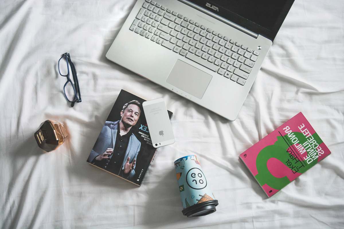 person flat lay photography of MacBook and book with eyeglasses people