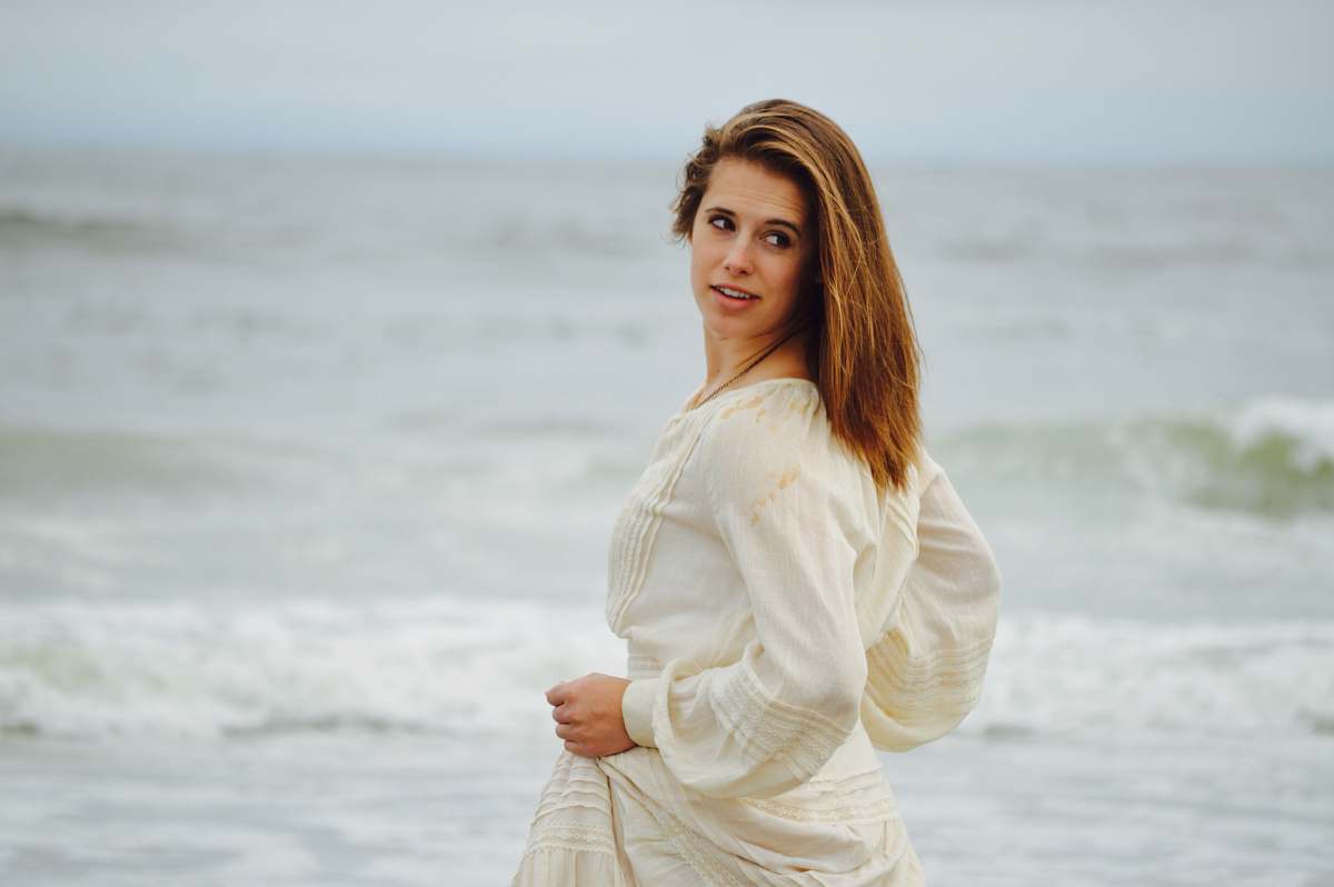 people focus photo of woman in white long-sleeved dress on seashore person