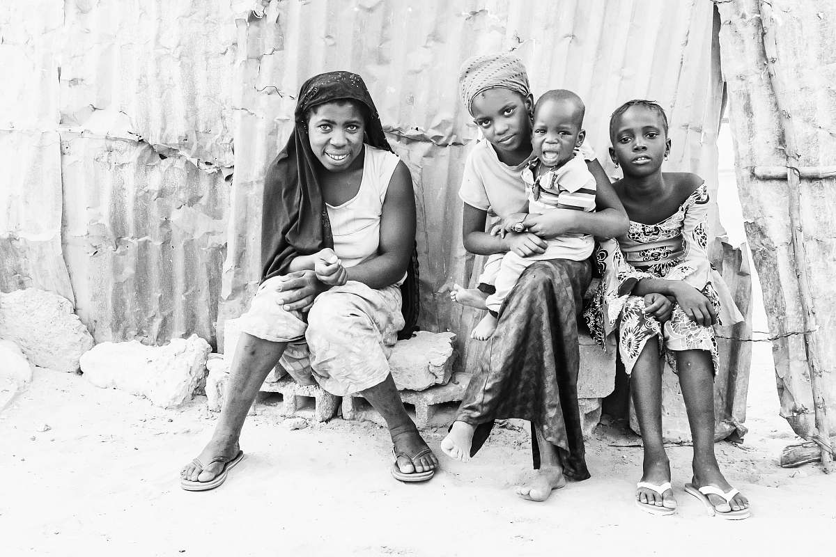 black-and-white grayscale photography of two smiling women sitting beside two kids face