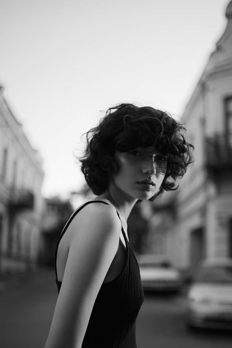 black-and-white grayscale photography of woman in black spaghetti strap top in middle of road people