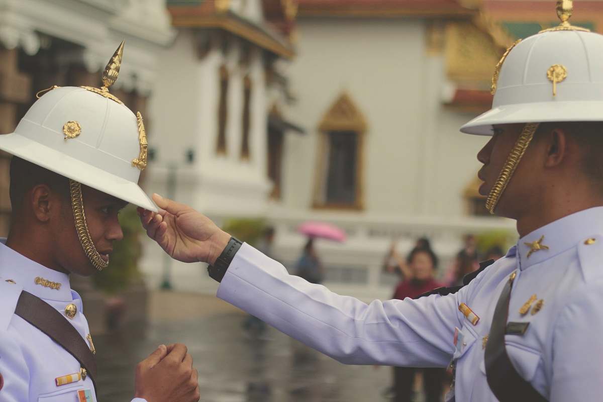 person officer in white uniform touching man's white hat people