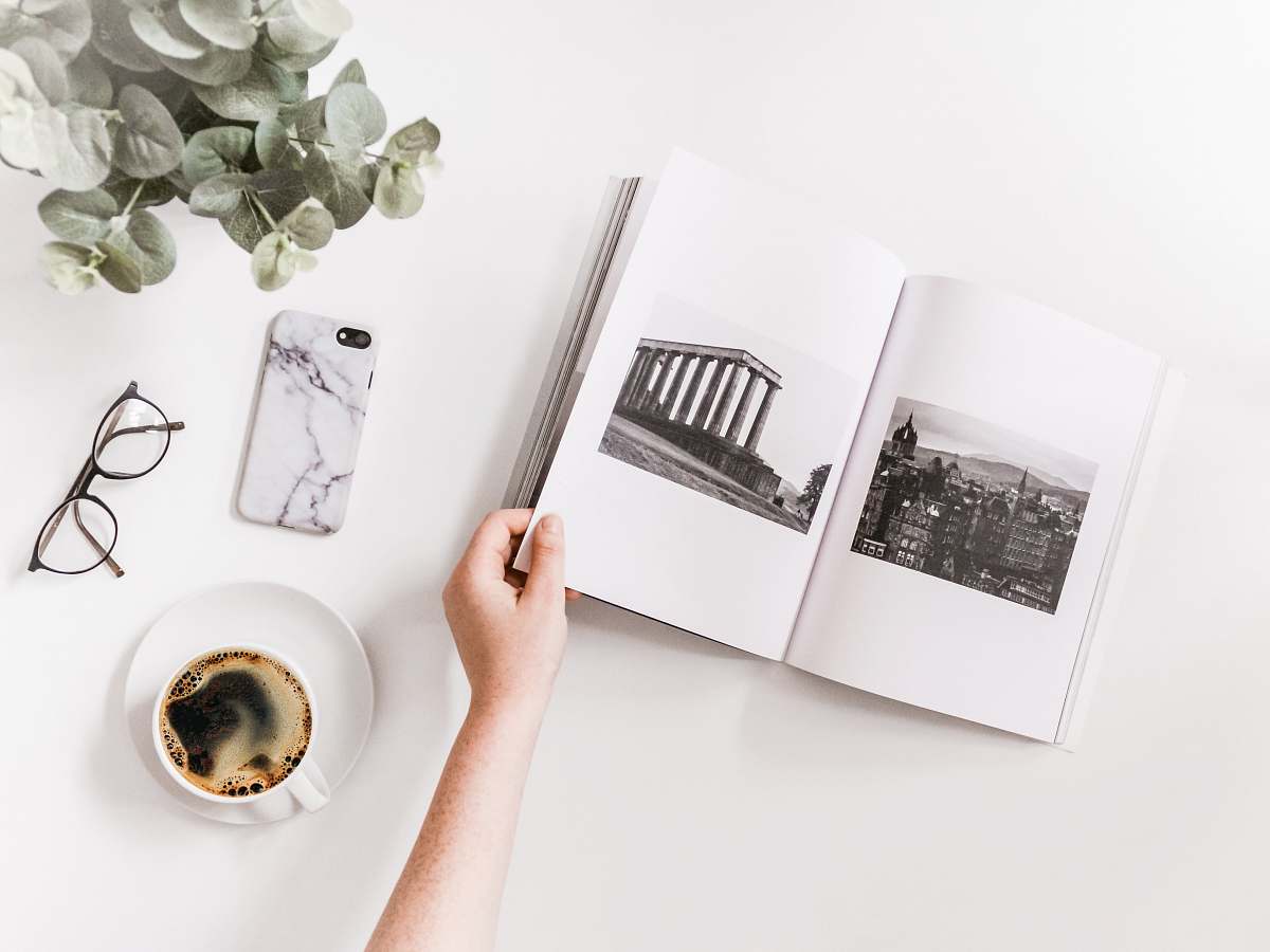 art person holding opened book beside iPhone drawing