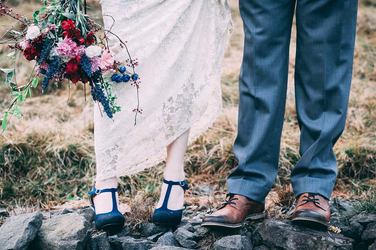 Capture the essence of love with this enchanting image of a bride and groom standing gracefully on rocks amidst a lush, wooded backdrop. The couple's joyous pose symbolizes their commitment, making this photograph an ideal choice for wedding invitations, romance-themed blogs, or any project celebrating love and nature. The natural elements surrounding them add a touch of serenity and adventure, perfect for those seeking to evoke emotions of happiness and celebration.