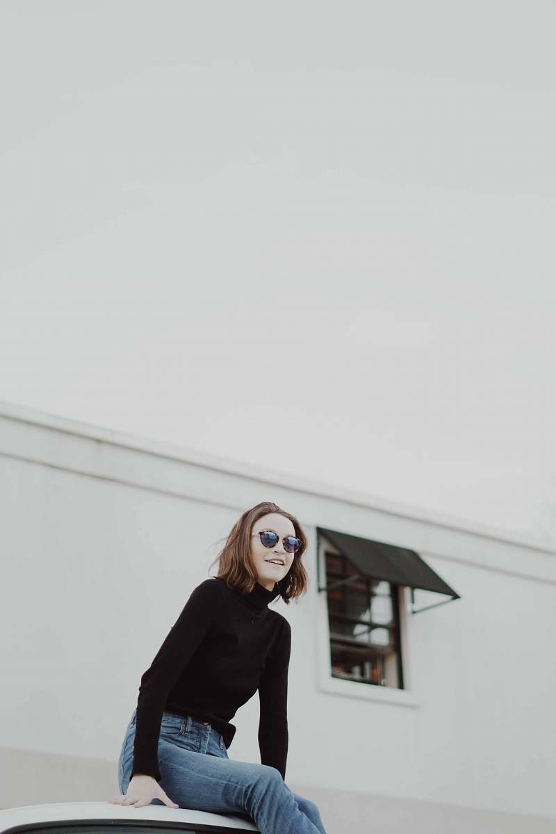 person woman in black sweatshirt in front of white building people