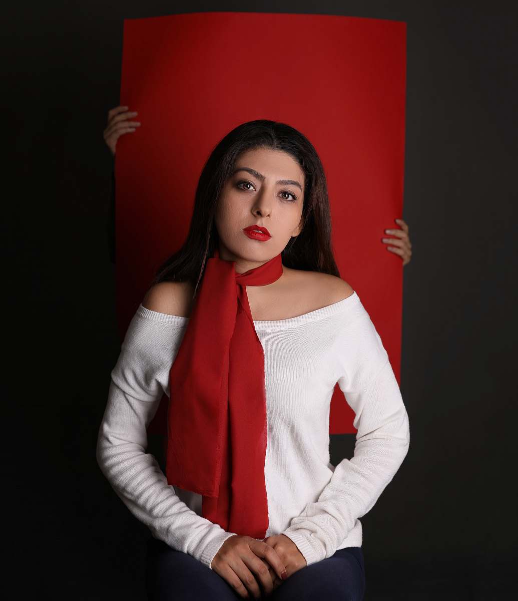 person woman in white long-sleeved top and red scarf in front of red paper board people