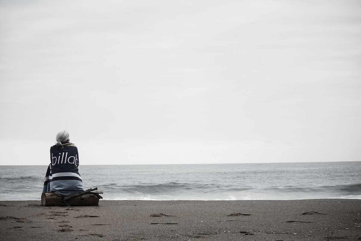 person woman sitting near seashore during daytime beach