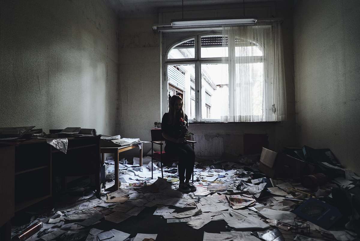 person woman sitting on chair surrounded by papers on floor flooring