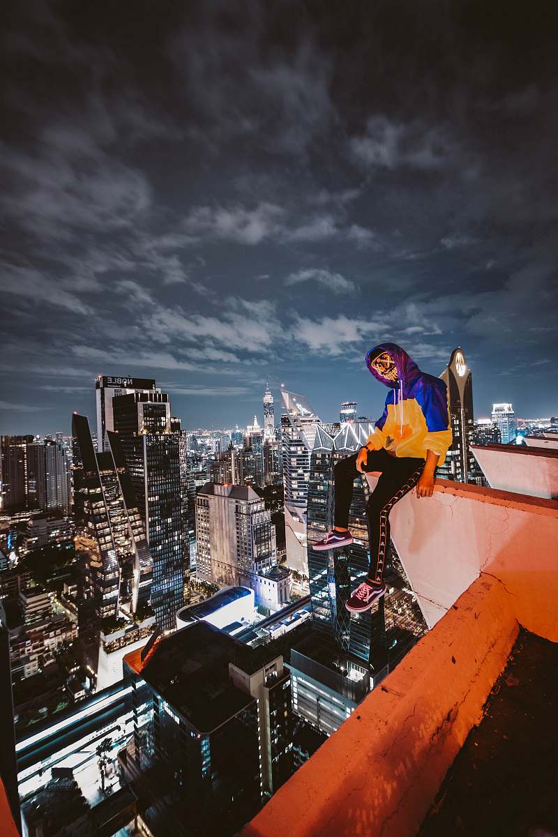 building woman sitting on cliff building city
