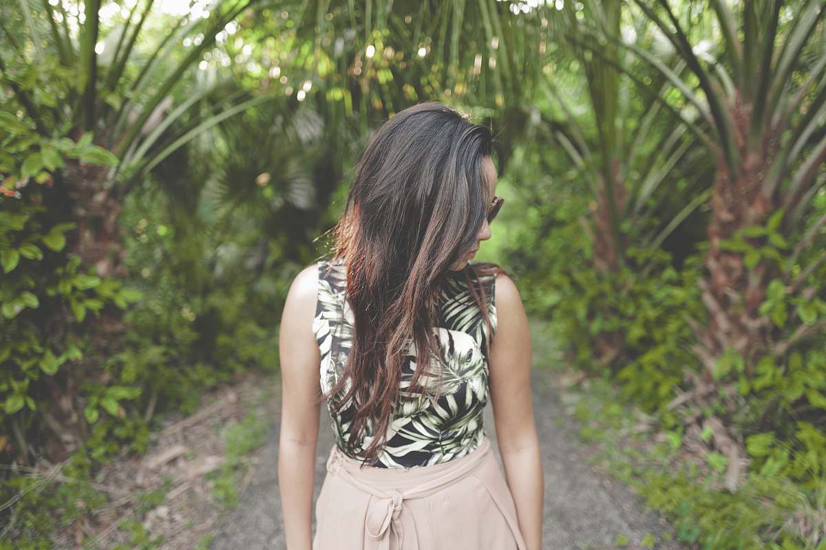 person woman walking on forest trail looking downwards forest