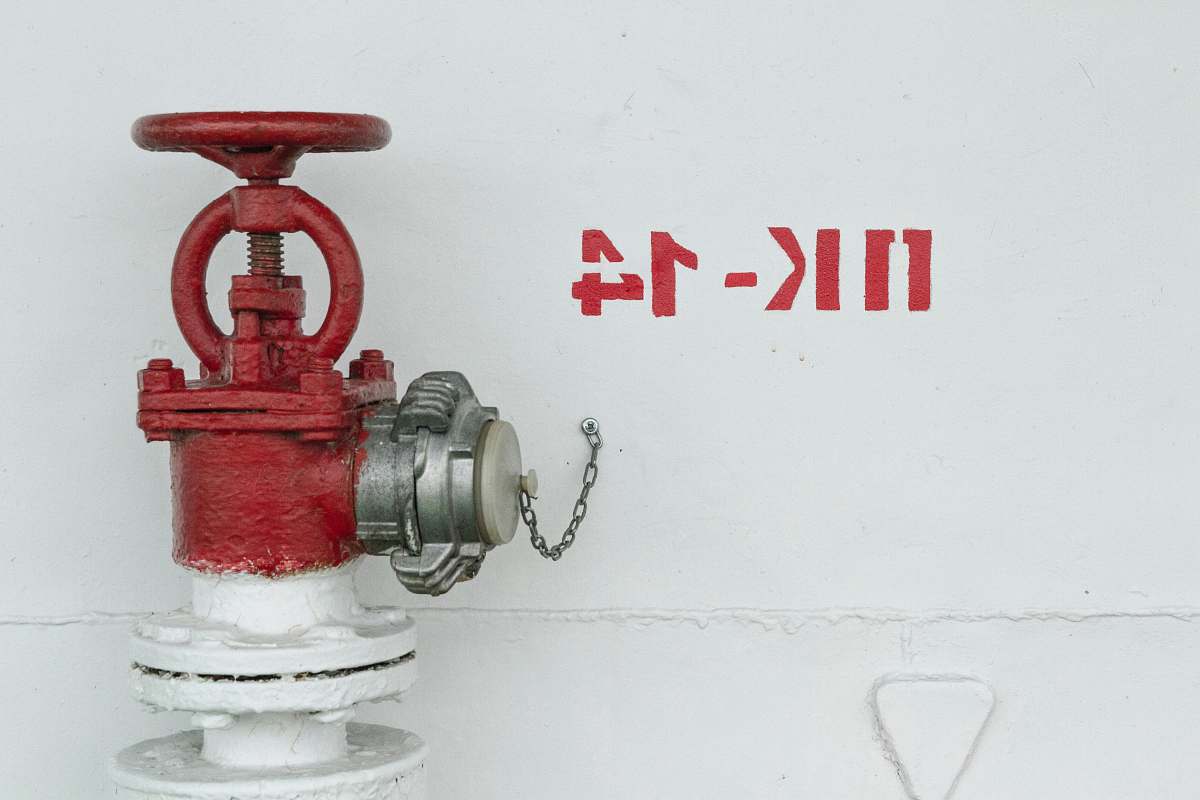 plumbing red and white fire hydrant beside white wall wall