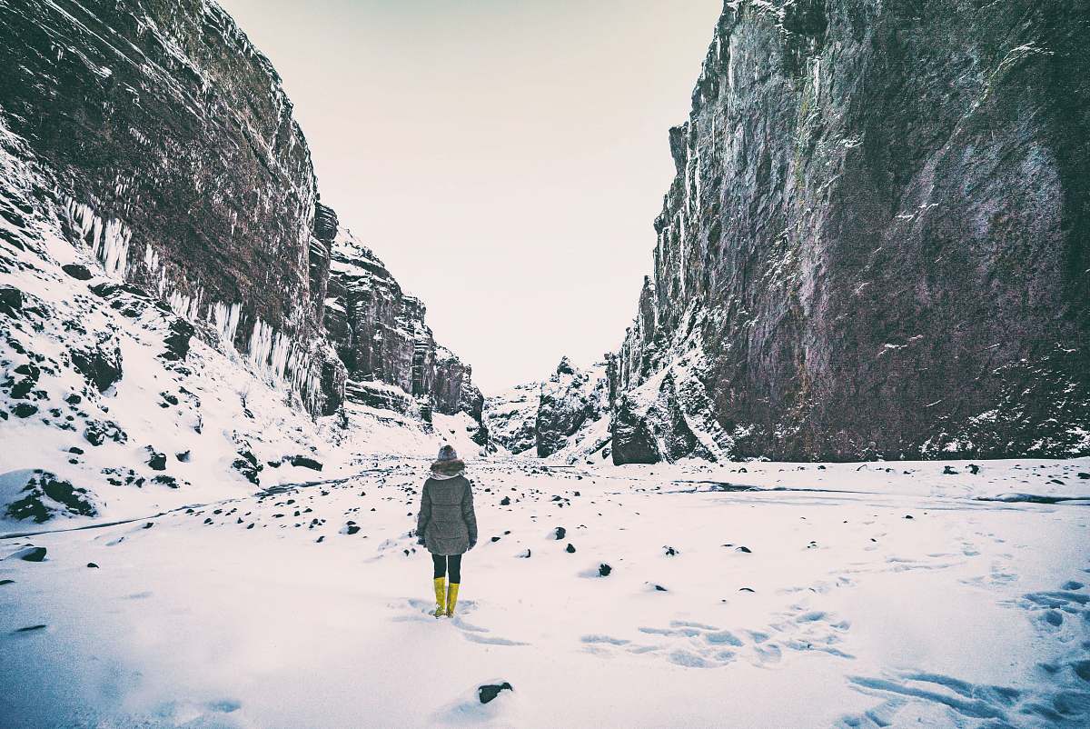 ice woman wearing gray coat standing in between mountain coated by snow nature