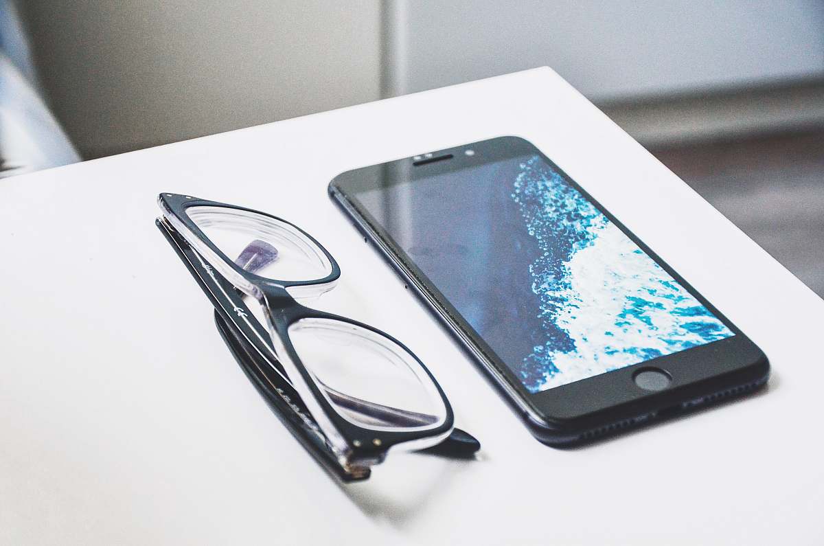 computer black eyeglasses near iPhone electronics