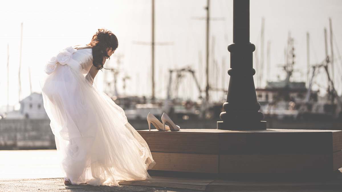 bride woman taking off her shoe near post white
