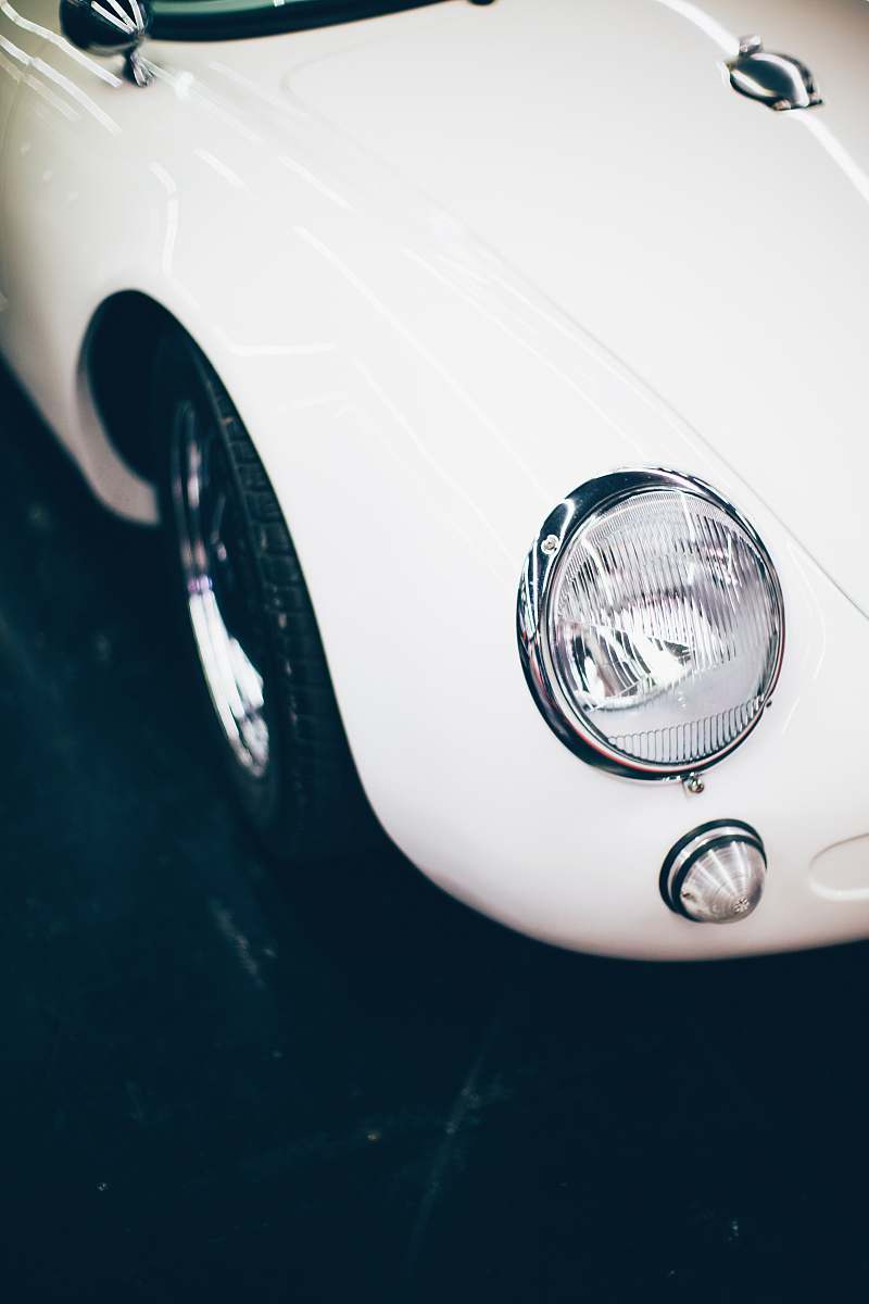 headlight white vehicle parked on black pavement vehicle