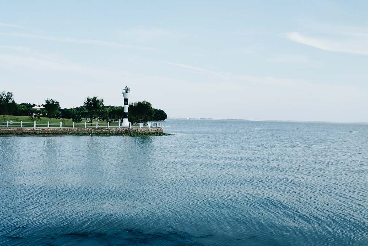 coast white and black light house beside of blue ocean during daytime ocean