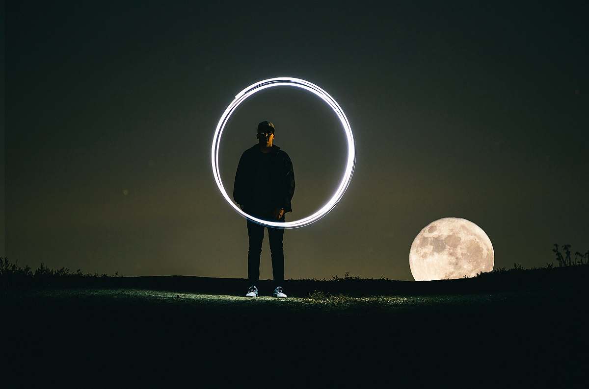 dark man standing on hill during full moon circle