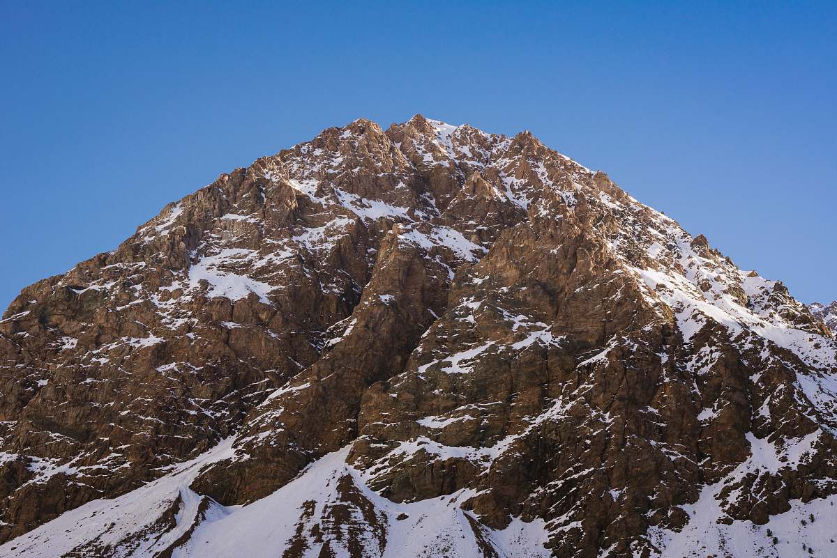 crest close up photo of brown snowcapped mountain at daytime mountain range