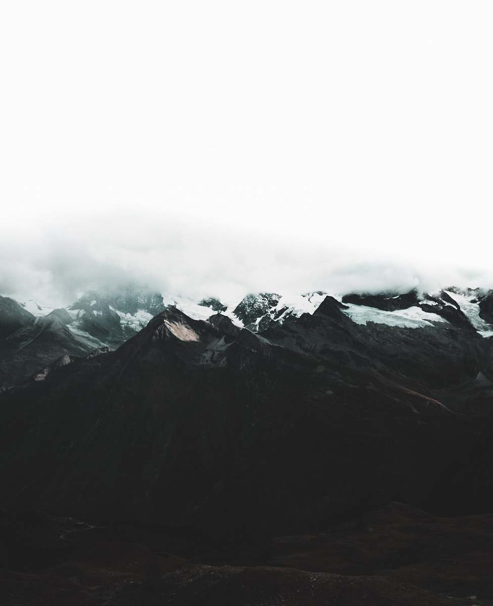 grey mountain range covered with snow and clouds at daytime nature