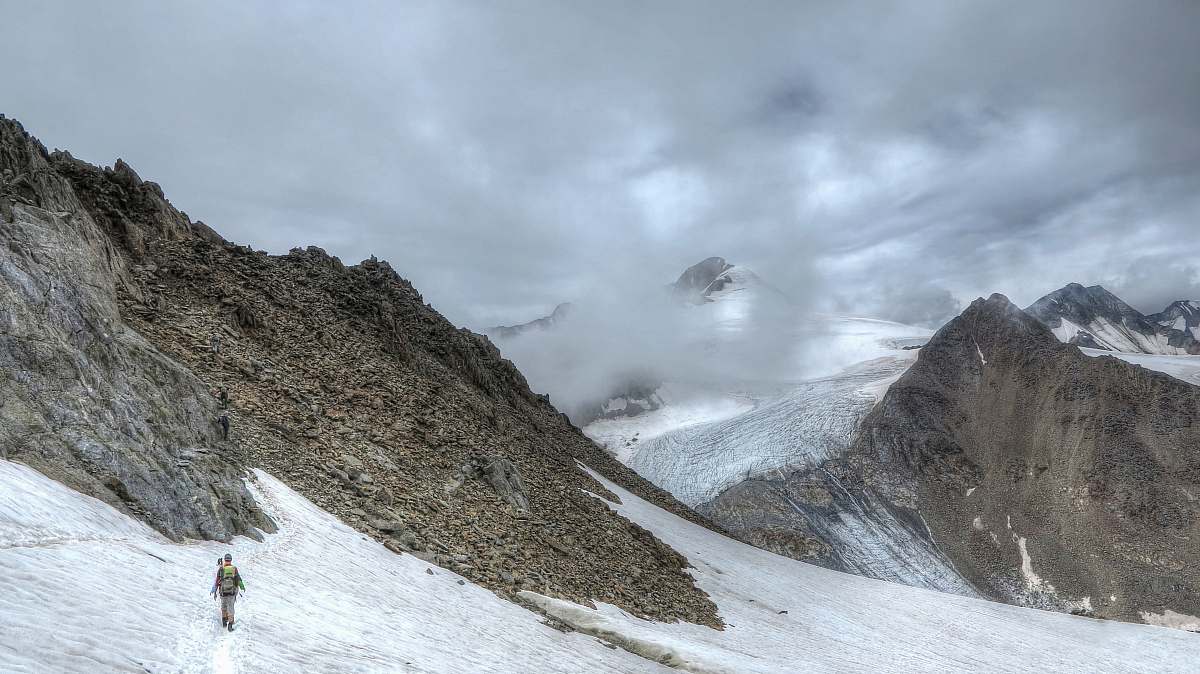 snow person walking on snow covered mountain during daytime glacier