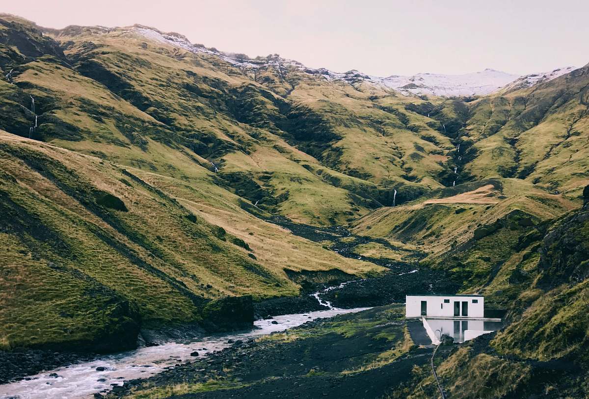 iceland white concrete house beside body of water in the mountain mountains