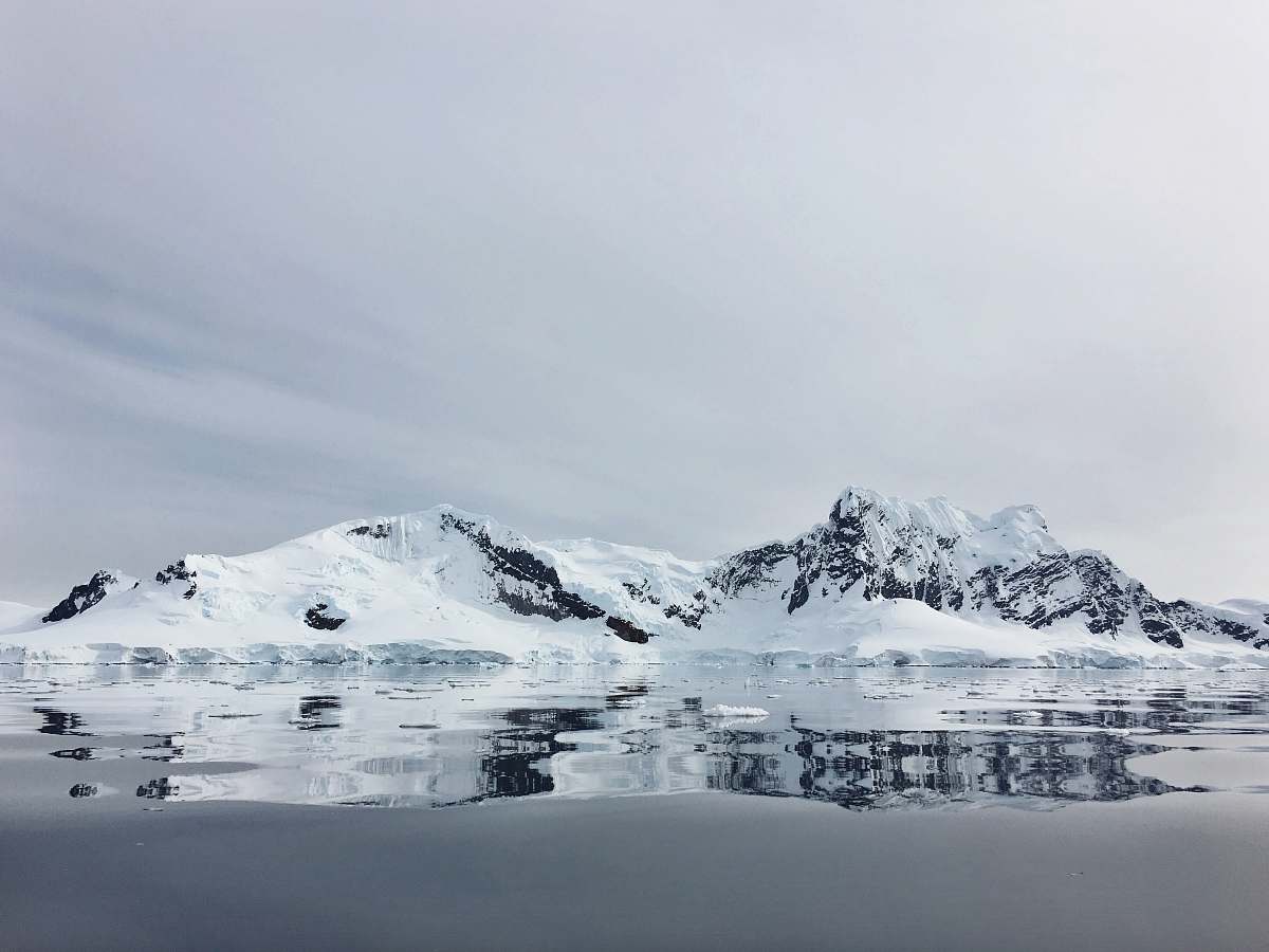 mountain body of water near snow capped mountain snow