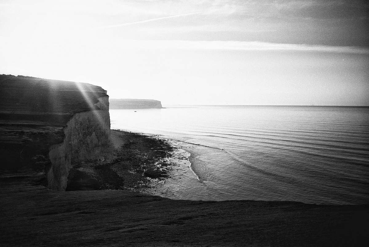 black-and-white grayscale photo of cliff and ocean outdoors