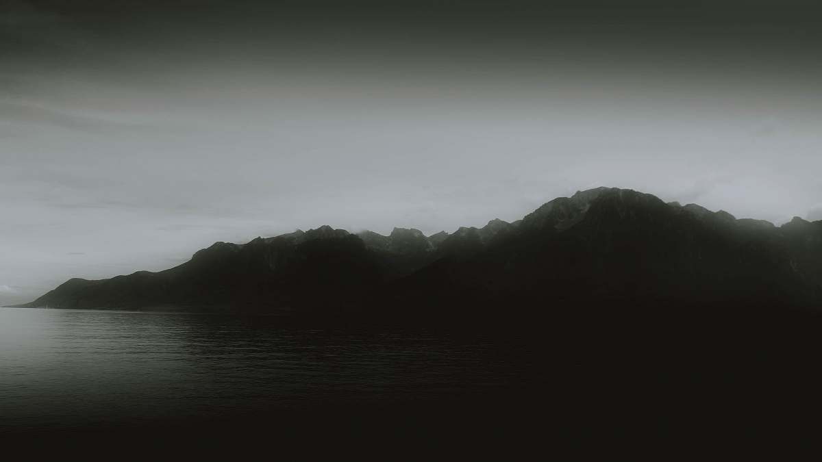 outdoors mountain range near body of water under foggy weather weather
