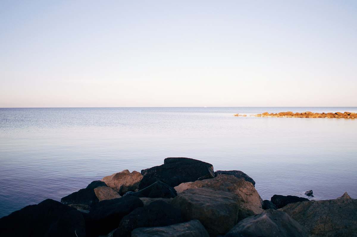 shoreline rocks beside body of water water