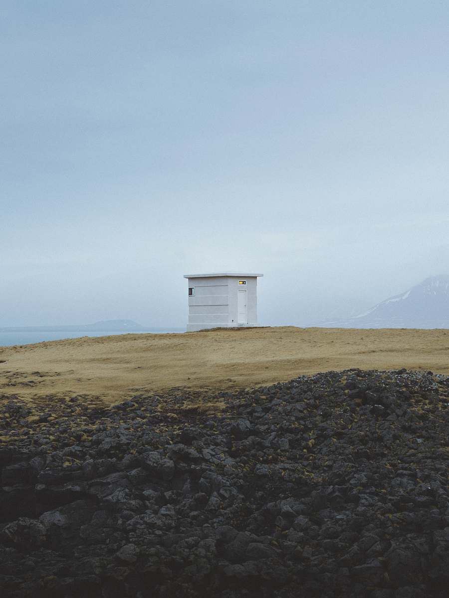 sea white wooden shed on top of hill iceland