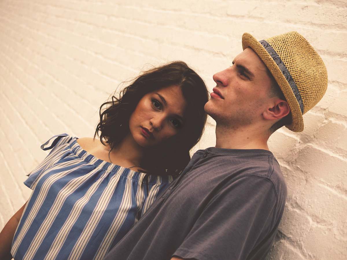 person man and woman standing near brick wall human