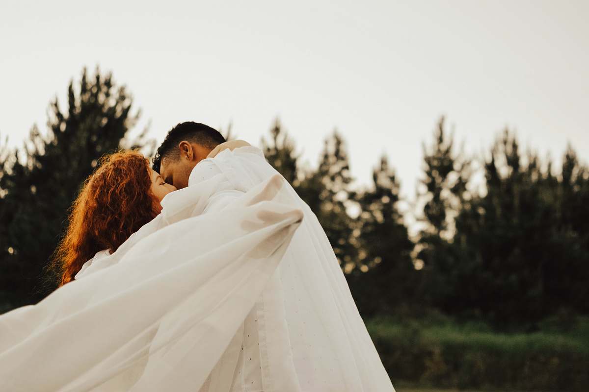 people man kissing woman in fabric during daytime human