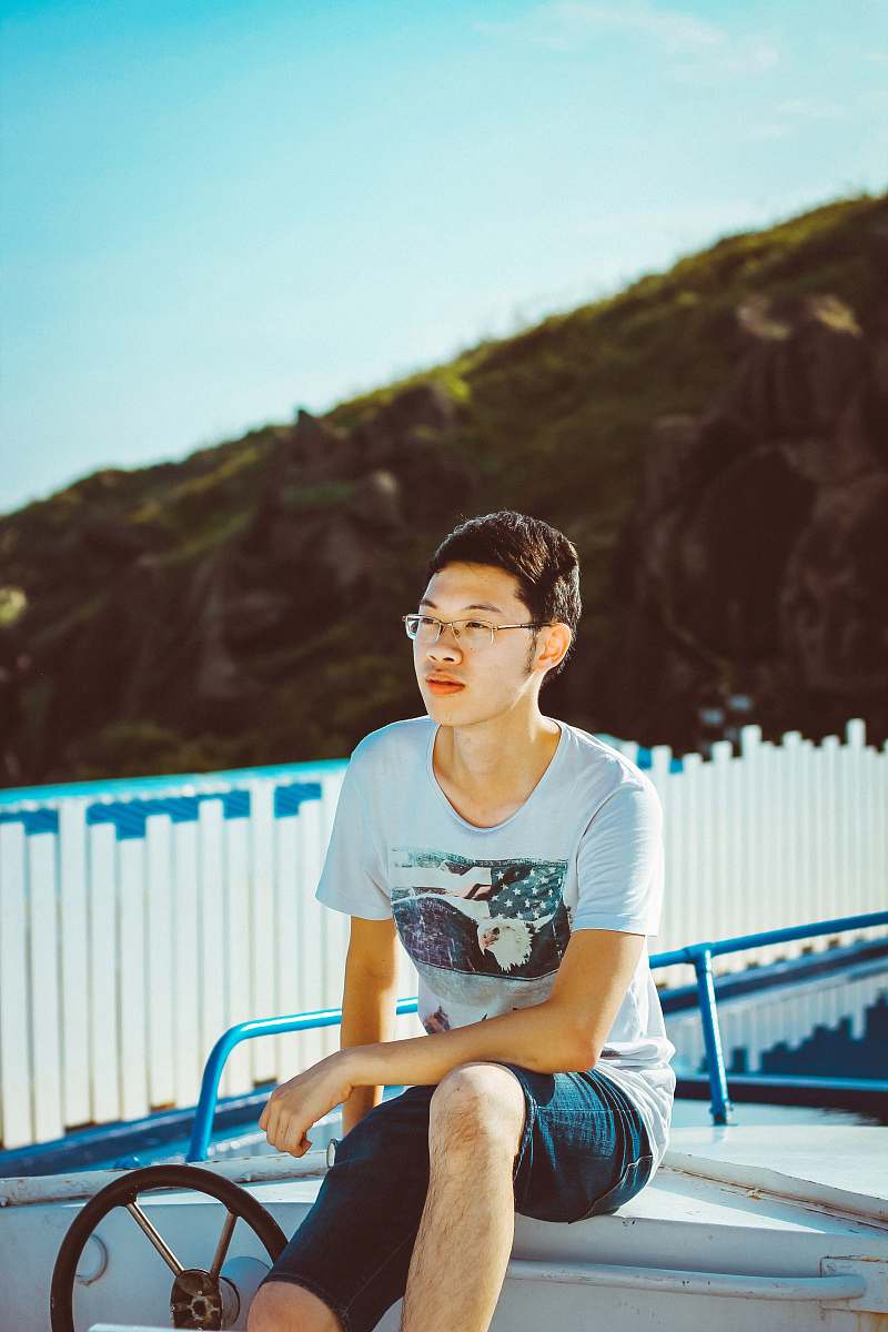 human man sitting near white wooden fence during daytime people