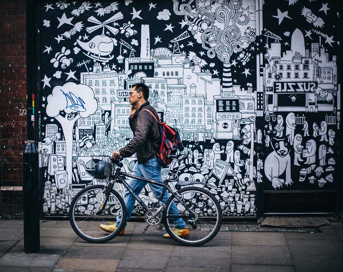 street man walking in street while wearing red backpack bike