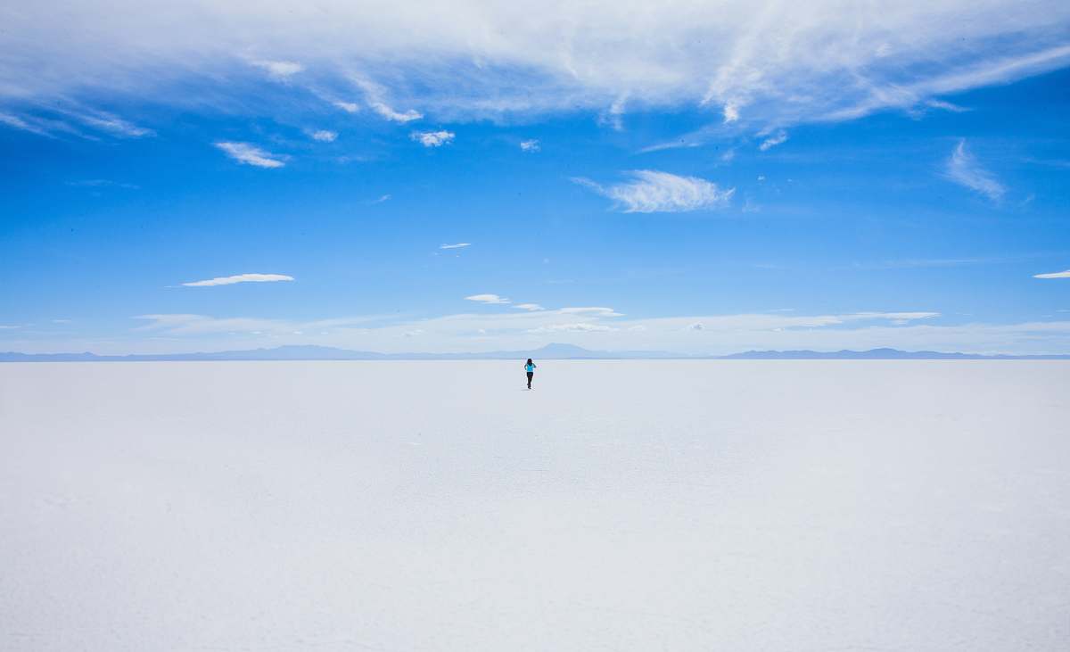blue person walking of sand covered field during daytime flat