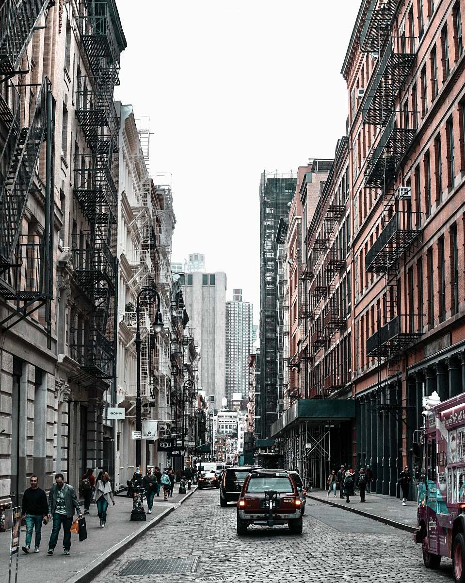 human vehicle on road between walking people and buildings pedestrian