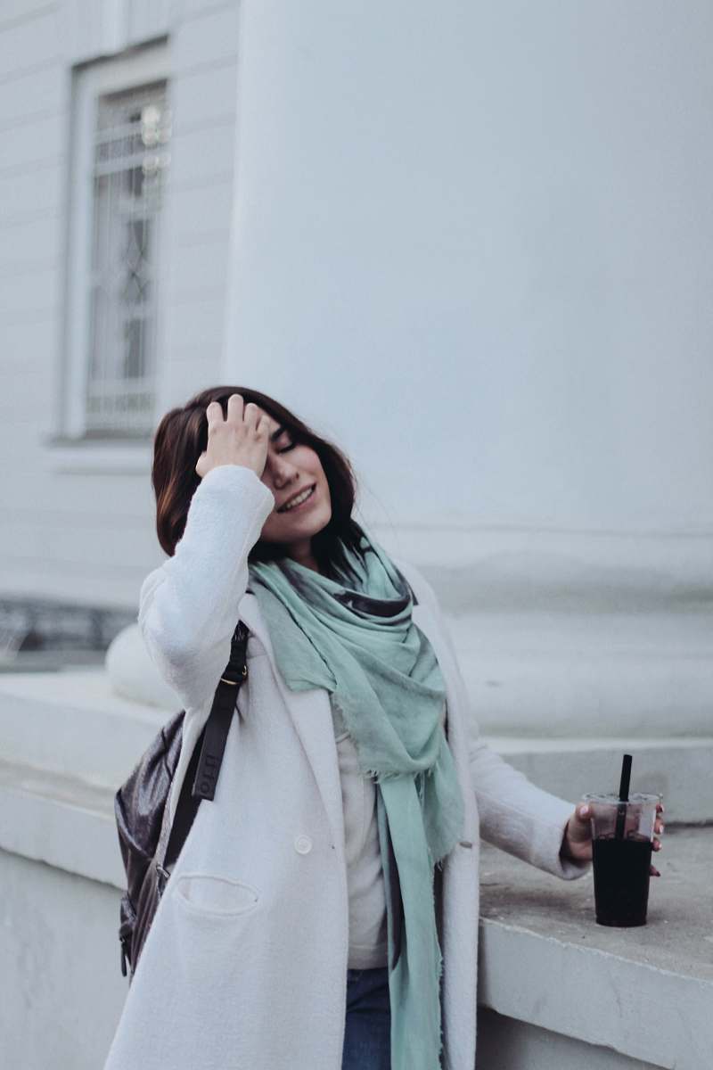people woman holding disposable cup near white painted building human