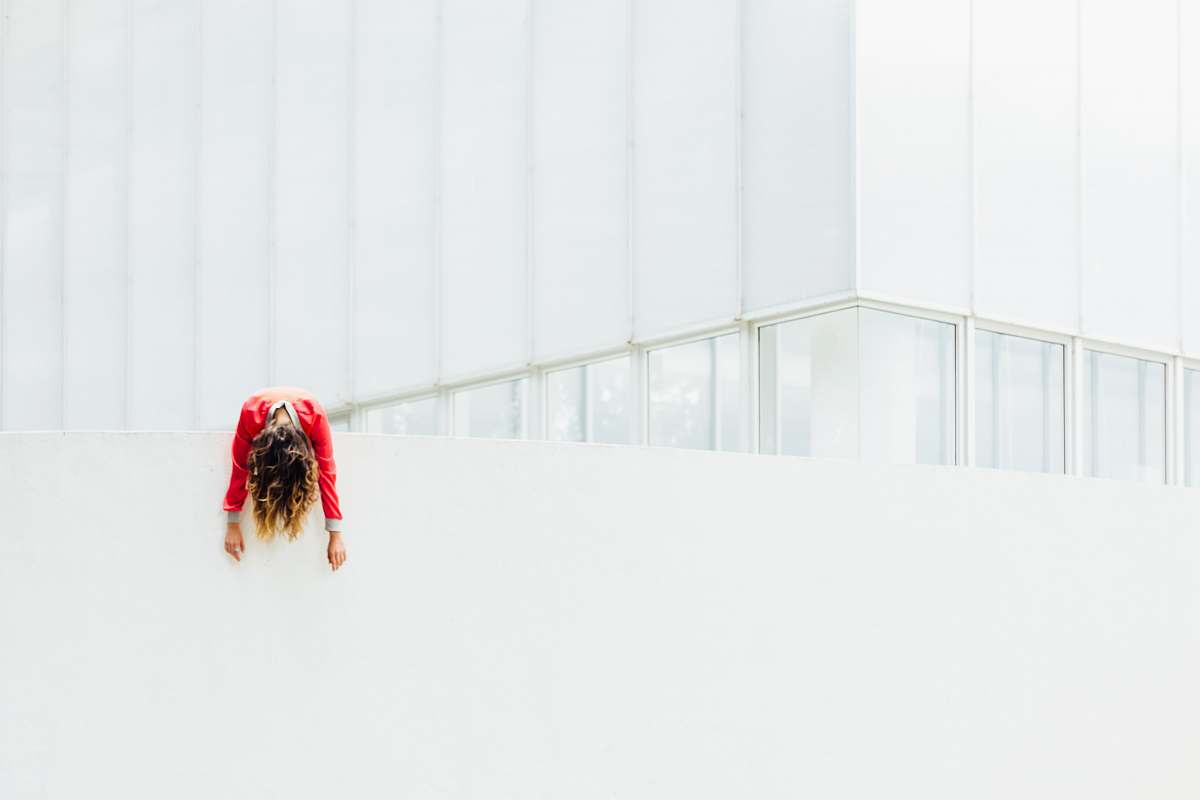 human woman in red jacket on white painted concrete railings building