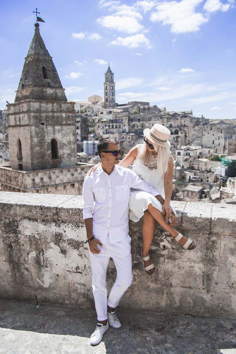 human woman sitting on concrete wall beside man at daytime people