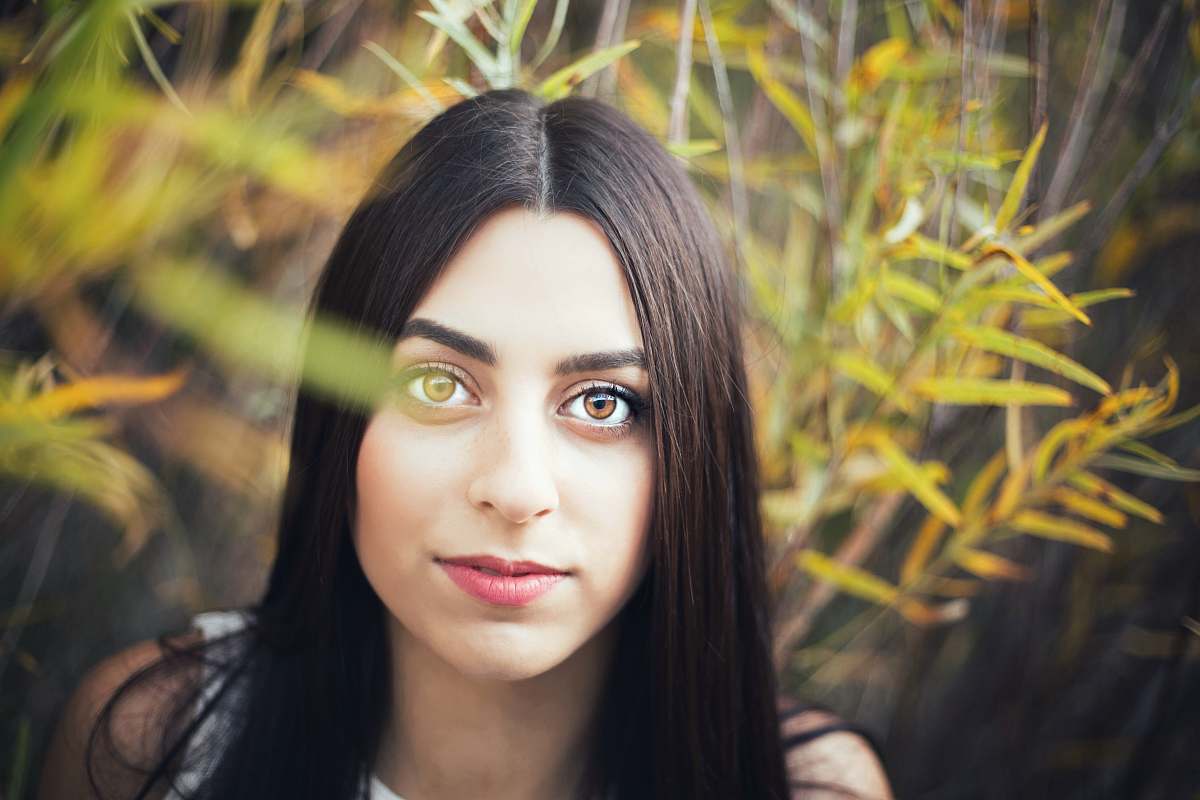 human woman with long black hair in front of green grass face