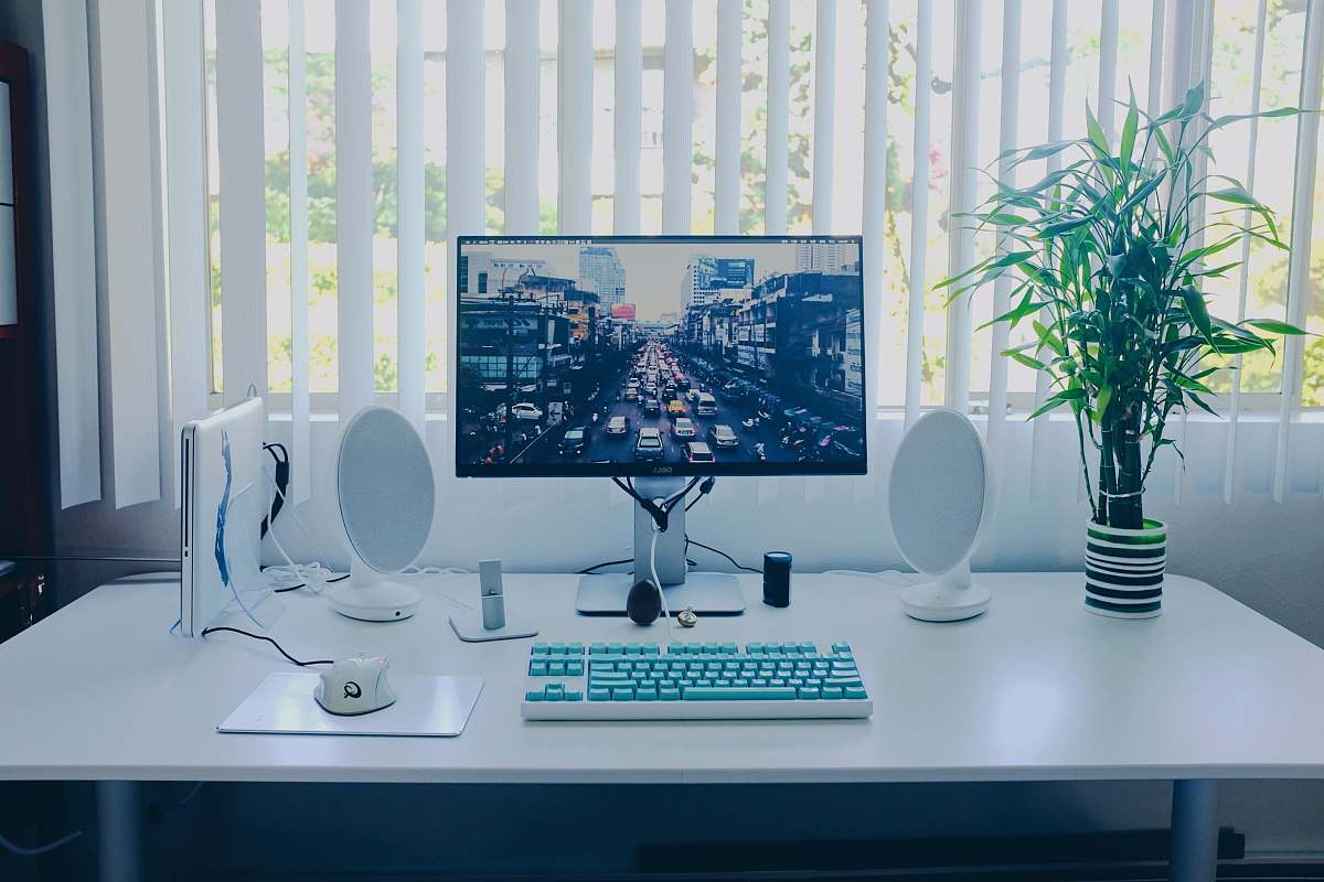 table black flat screen computer monitor; keyboard; speakers; mouse on desk desk