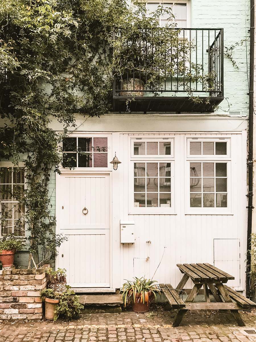ivy white and brown wooden house beside picnic table with green leaf plants flora