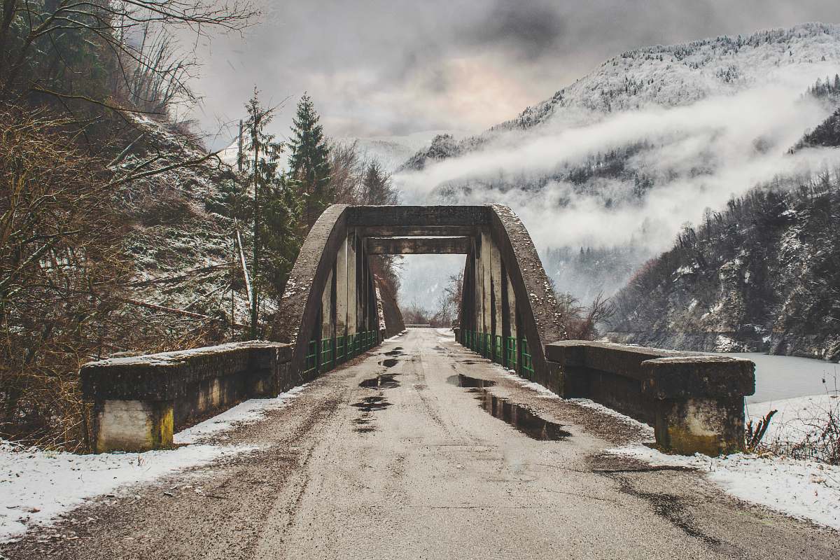 nature gray concrete arch bride beside leafless tree near mountain range bridge
