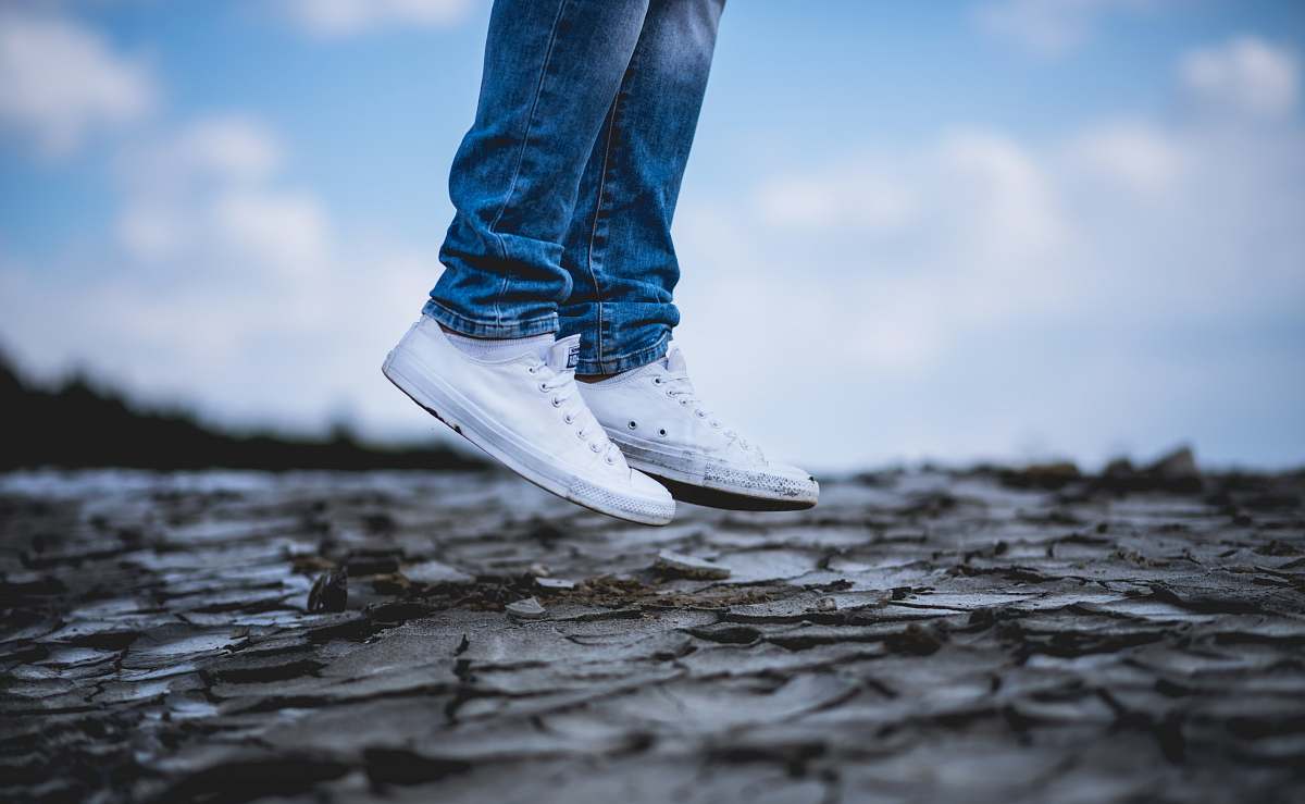 blue person wearing white low-top sneakers jump